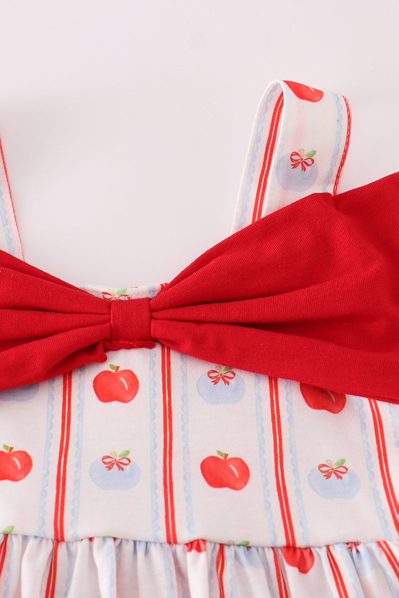 Close-up of red apple print fabric, ruffle edges, and bow detail on a girls' shorts set.