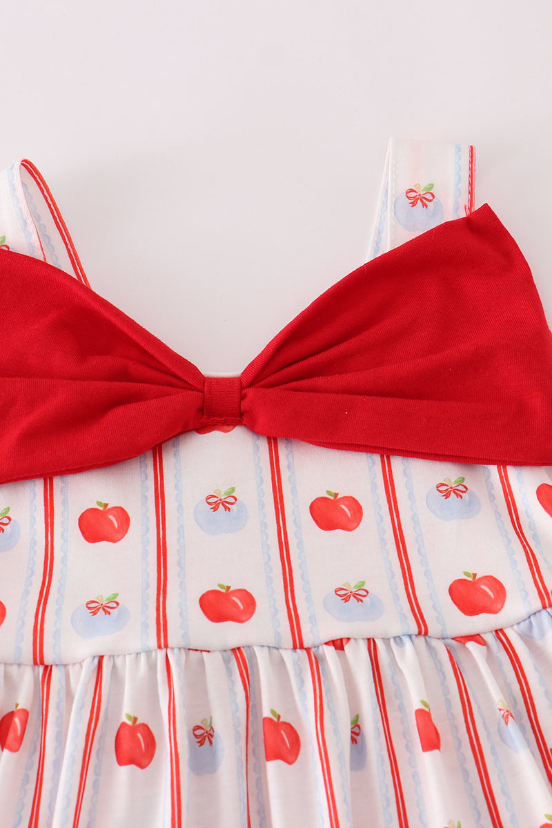 Close-up of red apple print fabric and a matching bow on a girls' dress.