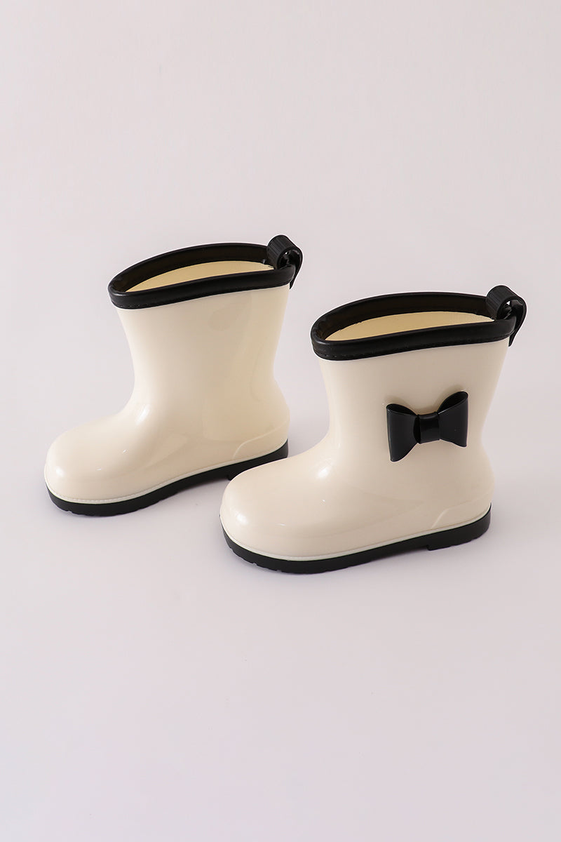 Girls' white and black rain boots with bow detail by Cloudling Kids Clothing.