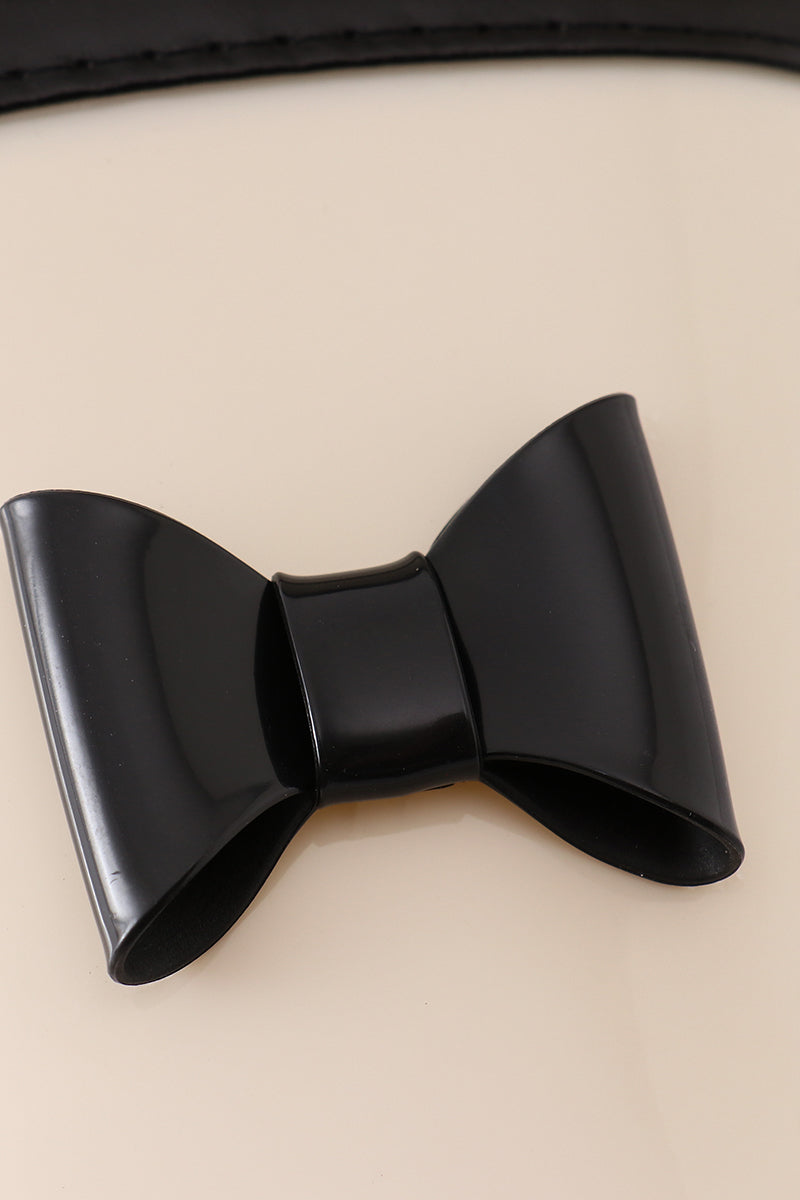 Close-up of a decorative black bow on white and black rain boots for children.