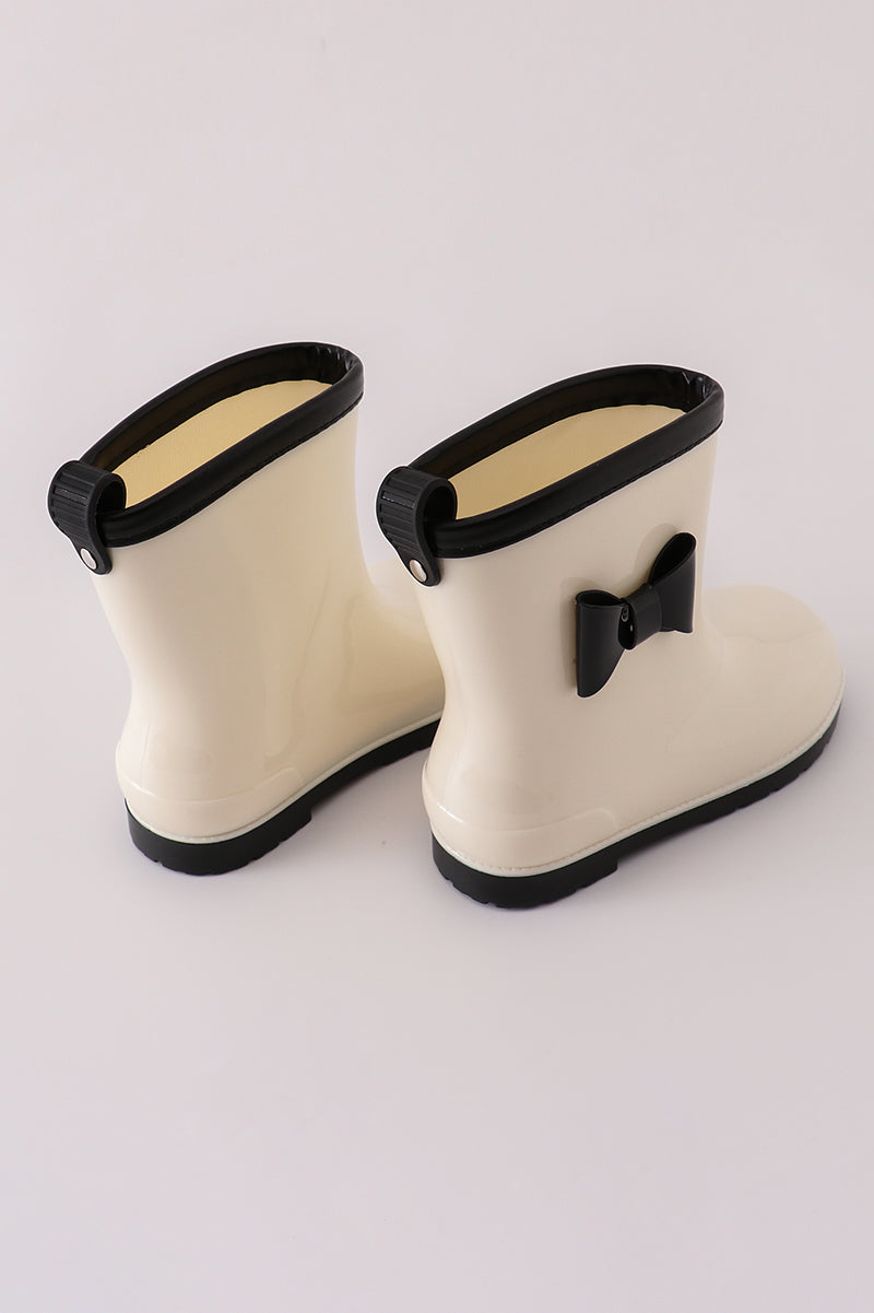Adorable white and black bow rain boots for kids, perfect for rainy days.