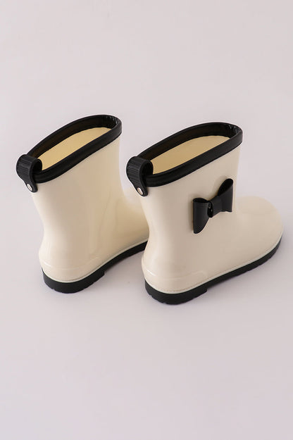 Adorable white and black bow rain boots for kids, perfect for rainy days.